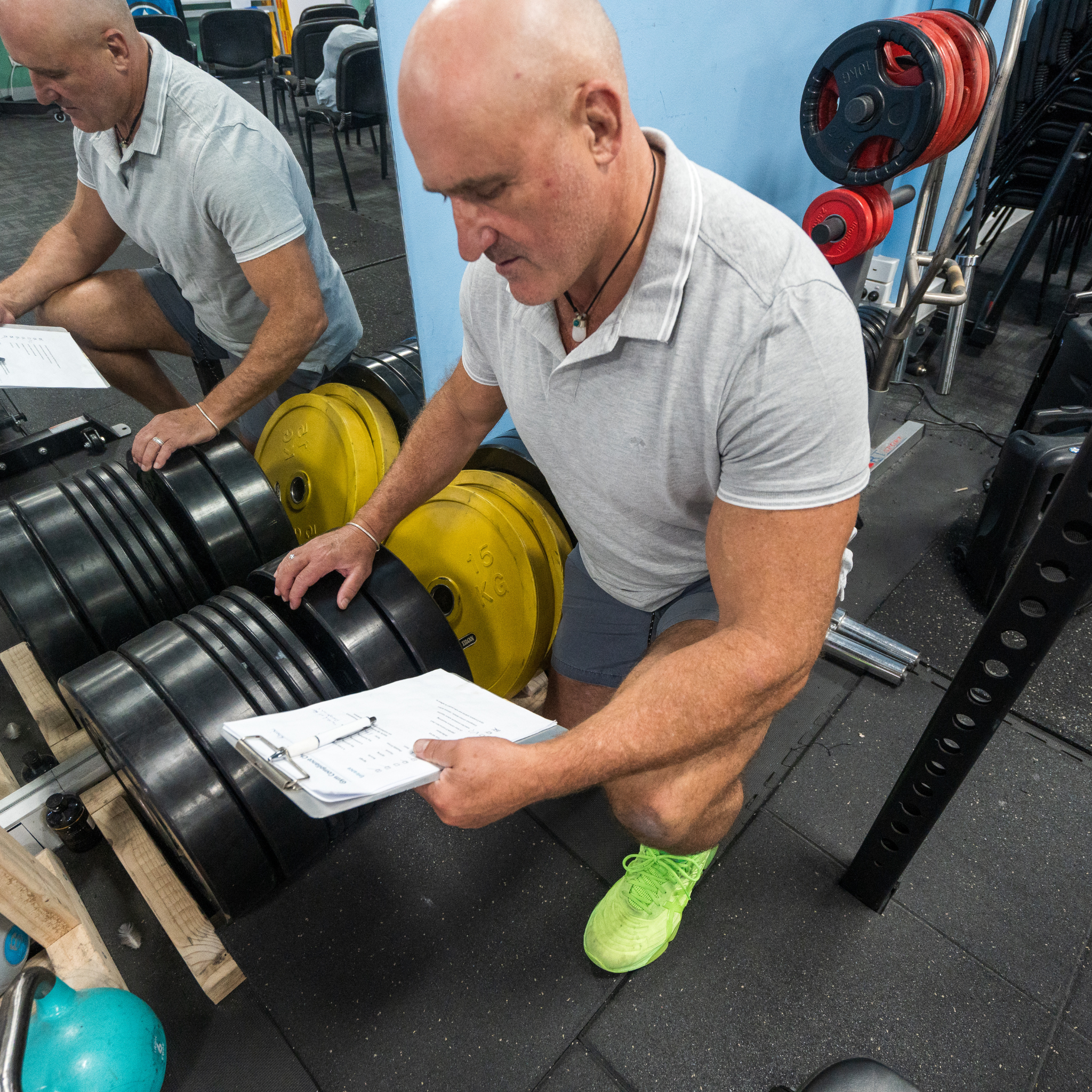 Man inspecting dumbbells in a gym as part of a gym health and safety check