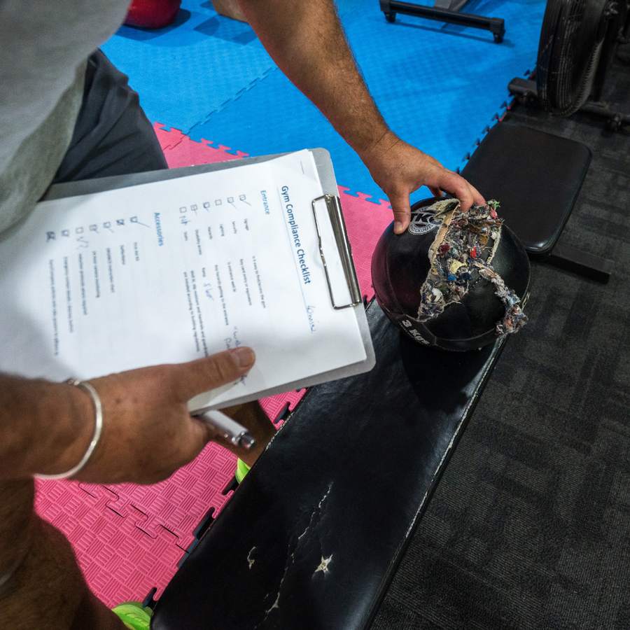 Gym risk assessment checklist being completed beside free weights in a fitness facility