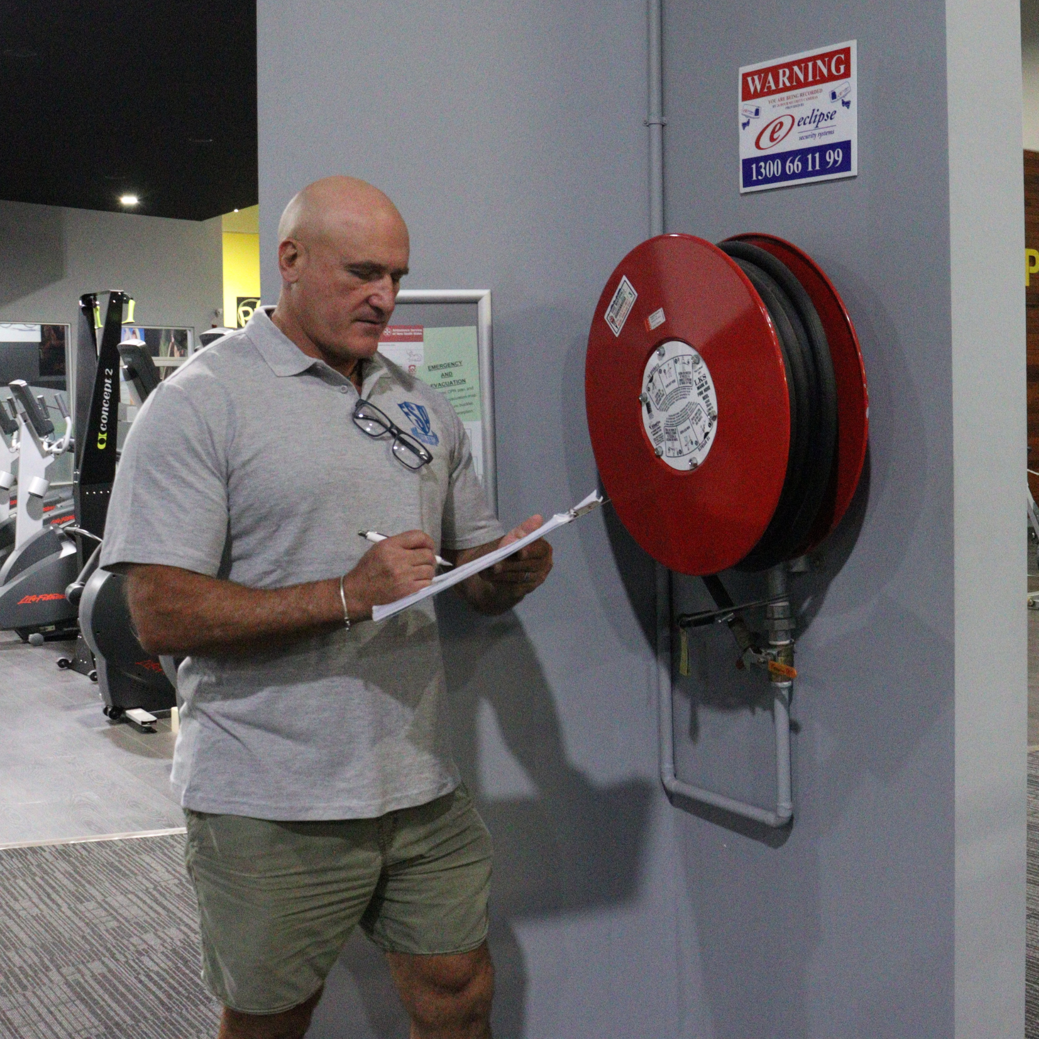 Gym operator using a gym risk assessment template and self-assessment scorecard near emergency equipment