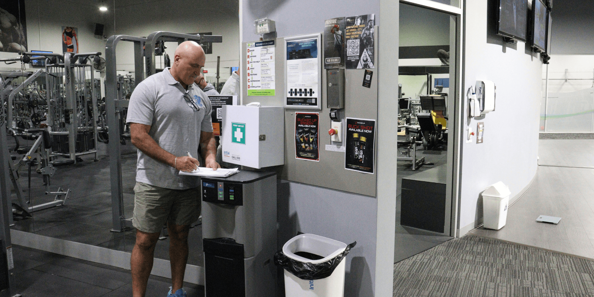 FitSafe Inspector reviewing safety systems in a gym with equipment and posters on the noticeboard.