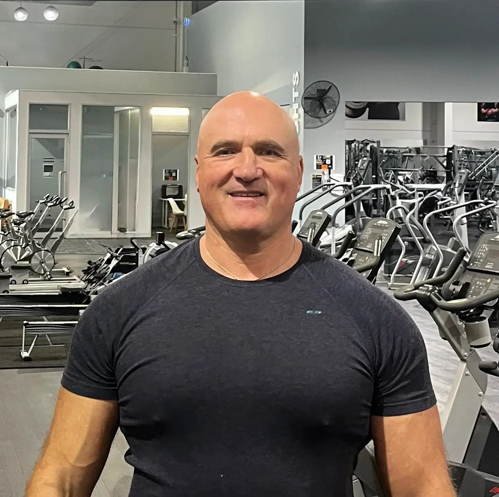 Man standing in a gym wearing a black t-shirt