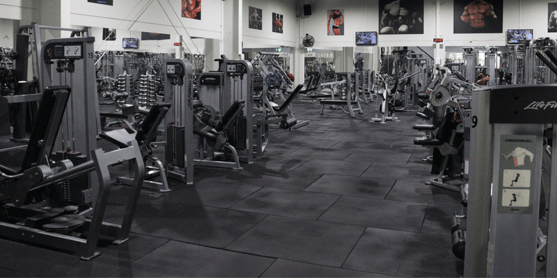 Gym interior with various exercise machines and equipment.