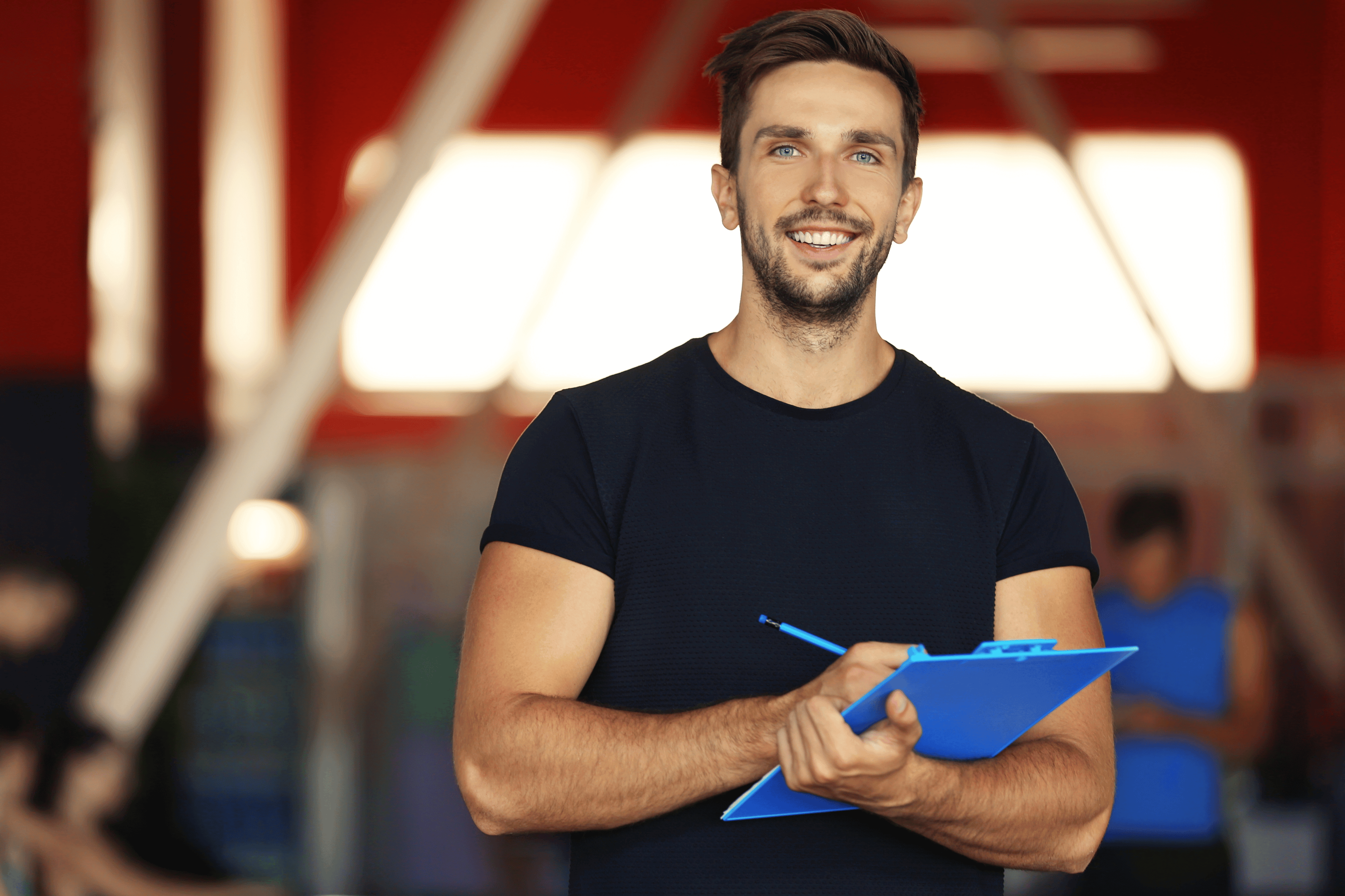 Man holding a blue clipboard in an indoor setting with blurred background